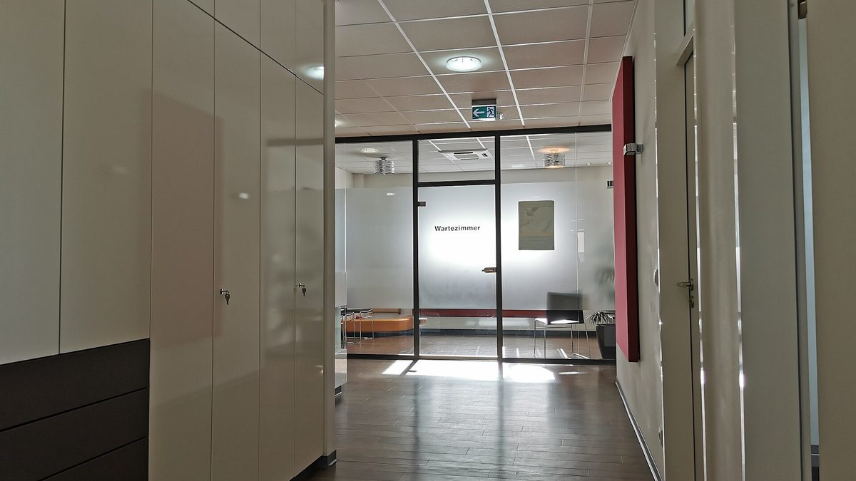 Heller Flur einer Arztpraxis mit Glastür zum Wartezimmer