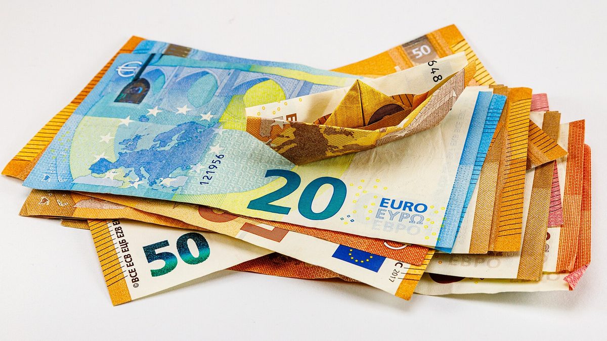 Mehrere Euro-Banknoten zu 20 und 50 Euro mit einem gefalteten Papierboot