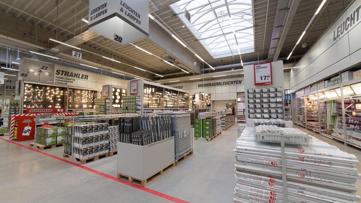 Heller Verkaufsraum eines Baumarkts mit Leuchtenabteilung, Regalen und Warenpaletten