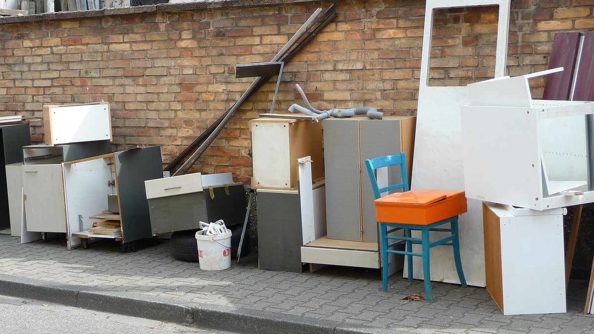 Ausrangierte Küchenschränke, Möbelteile und ein Stuhl als Sperrmüll am Straßenrand