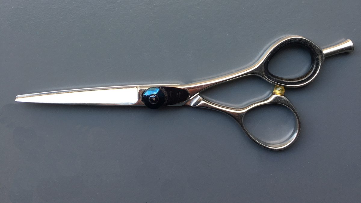 Professionelle Friseurschere auf grauem Hintergrund