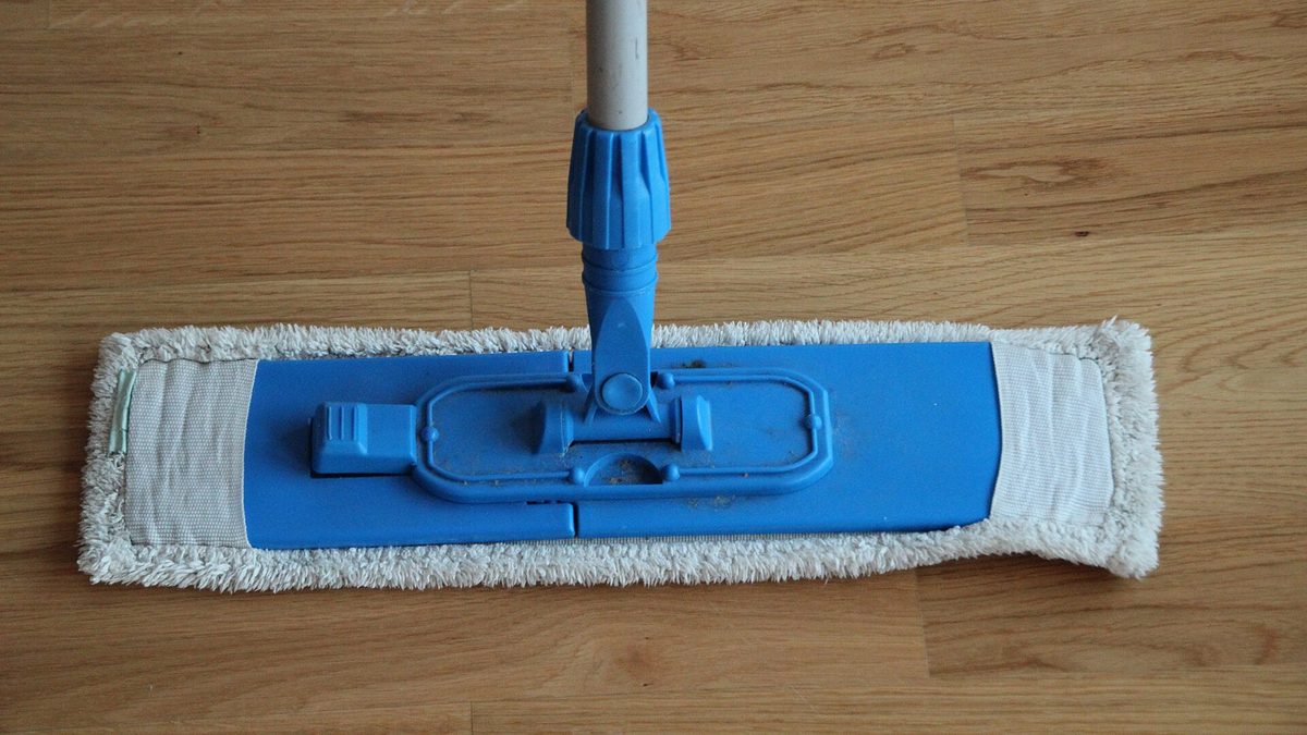 Blauer Flachmopp mit weißem Mikrofaserbezug auf einem hellen Holzboden
