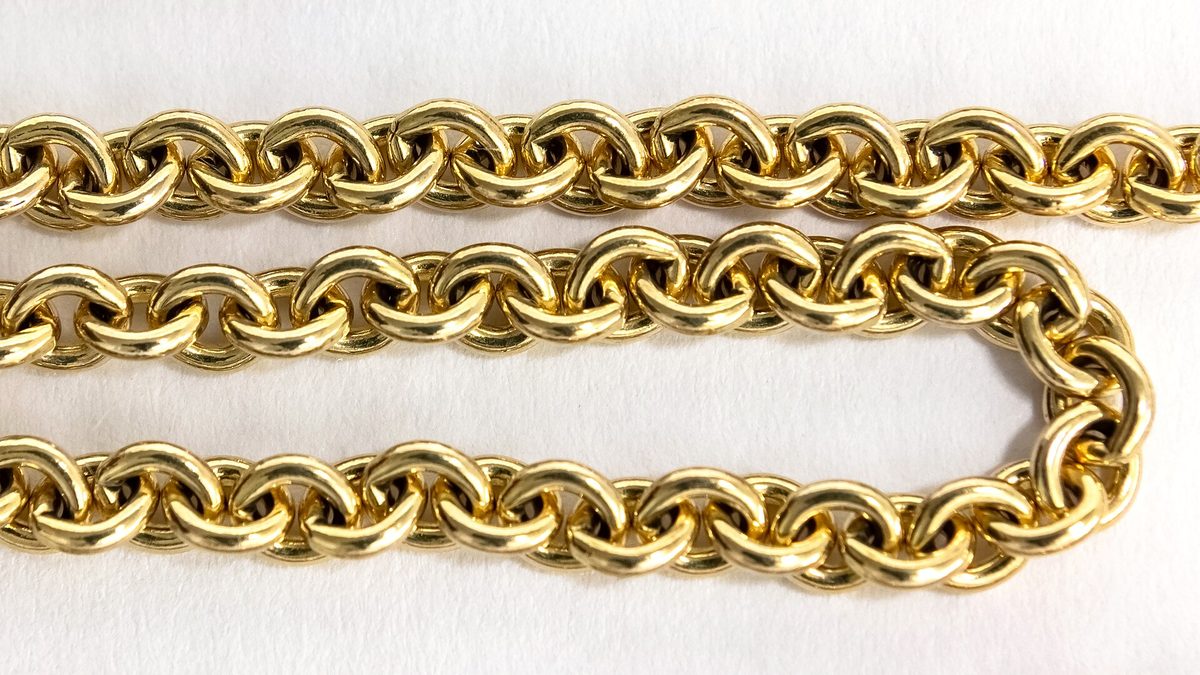Nahaufnahme einer glänzenden Goldkette mit runden Gliedern auf weißem Grund