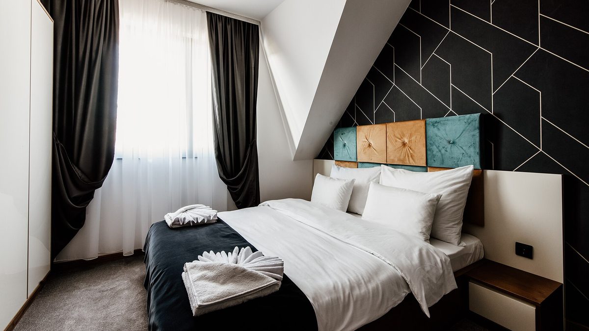 Helles Hotelzimmer mit Doppelbett, weißer Bettwäsche und gefalteten Handtüchern