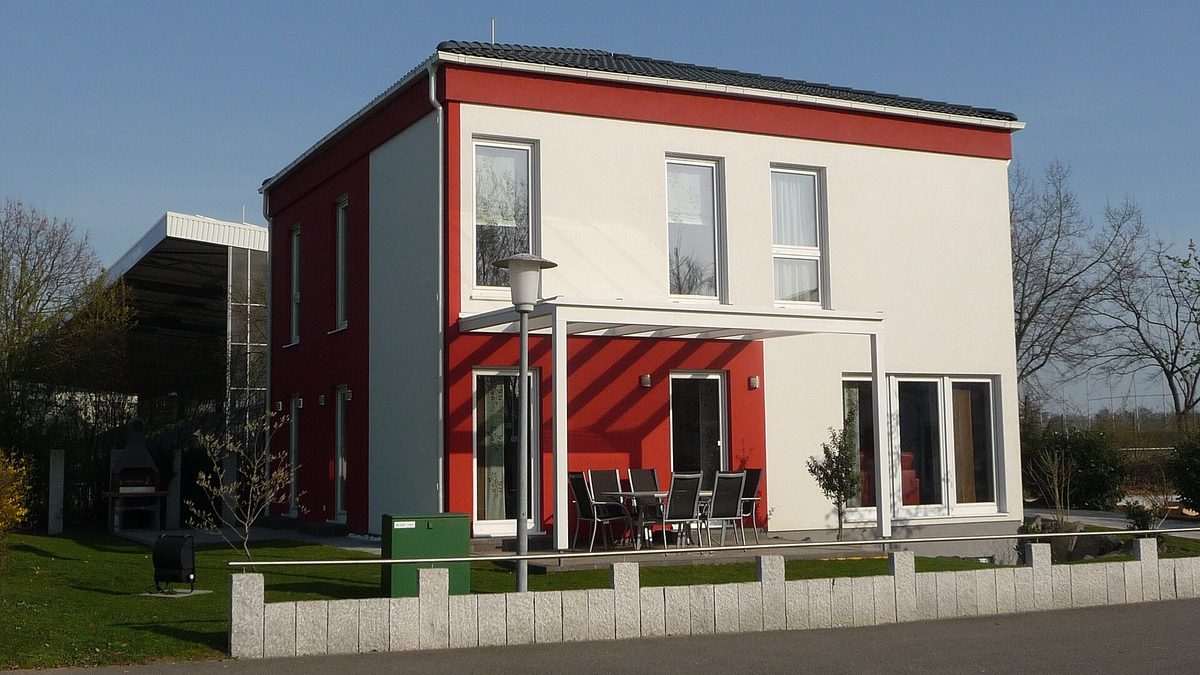 Modernes zweigeschossiges Einfamilienhaus mit Terrasse, Rasen und blauem Himmel