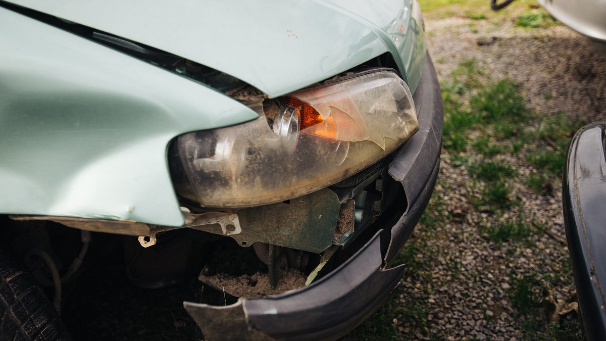Beschädigte Fahrzeugfront mit gebrochenem Scheinwerfer und abgerissener Stoßstange nach einem Unfall
