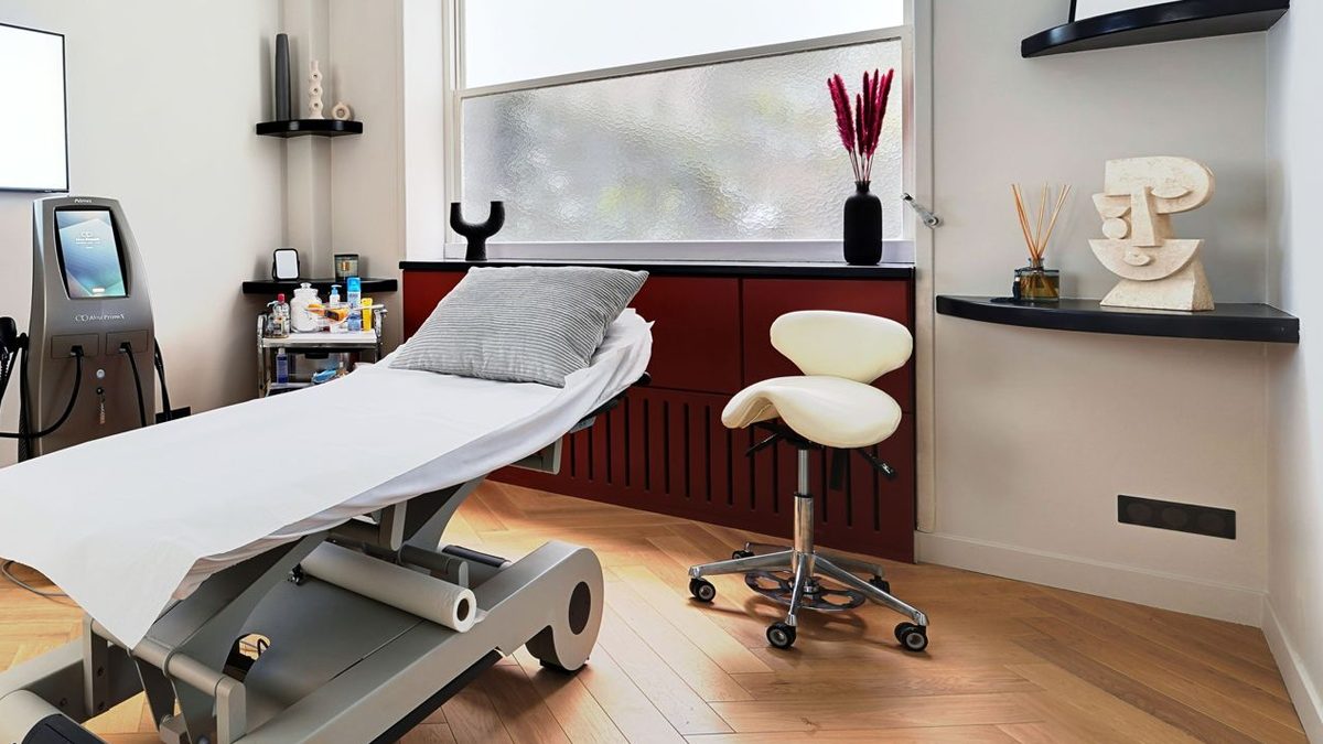 Heller Behandlungsraum eines Laserstudios mit Liege, Lasergerät und Sattelhocker