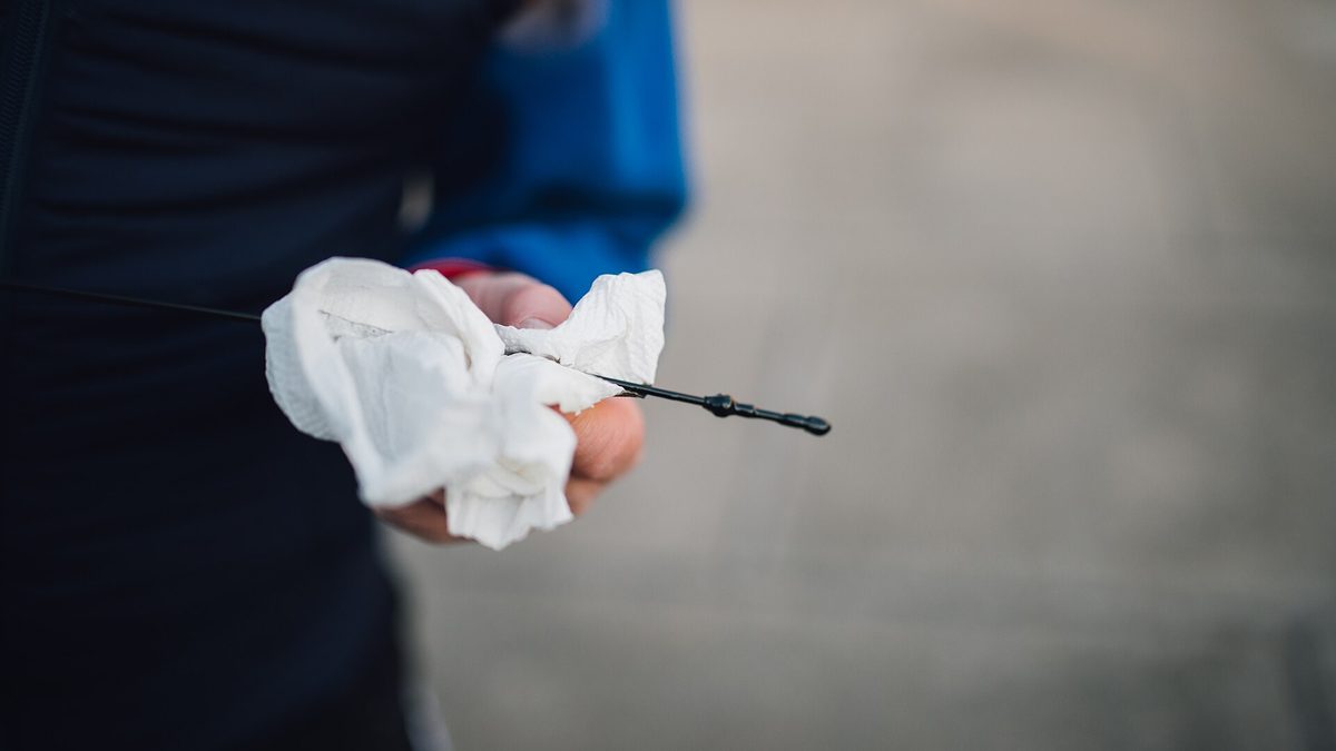 Hand hält Ölmessstab und Papiertuch beim Prüfen des Motorölstands