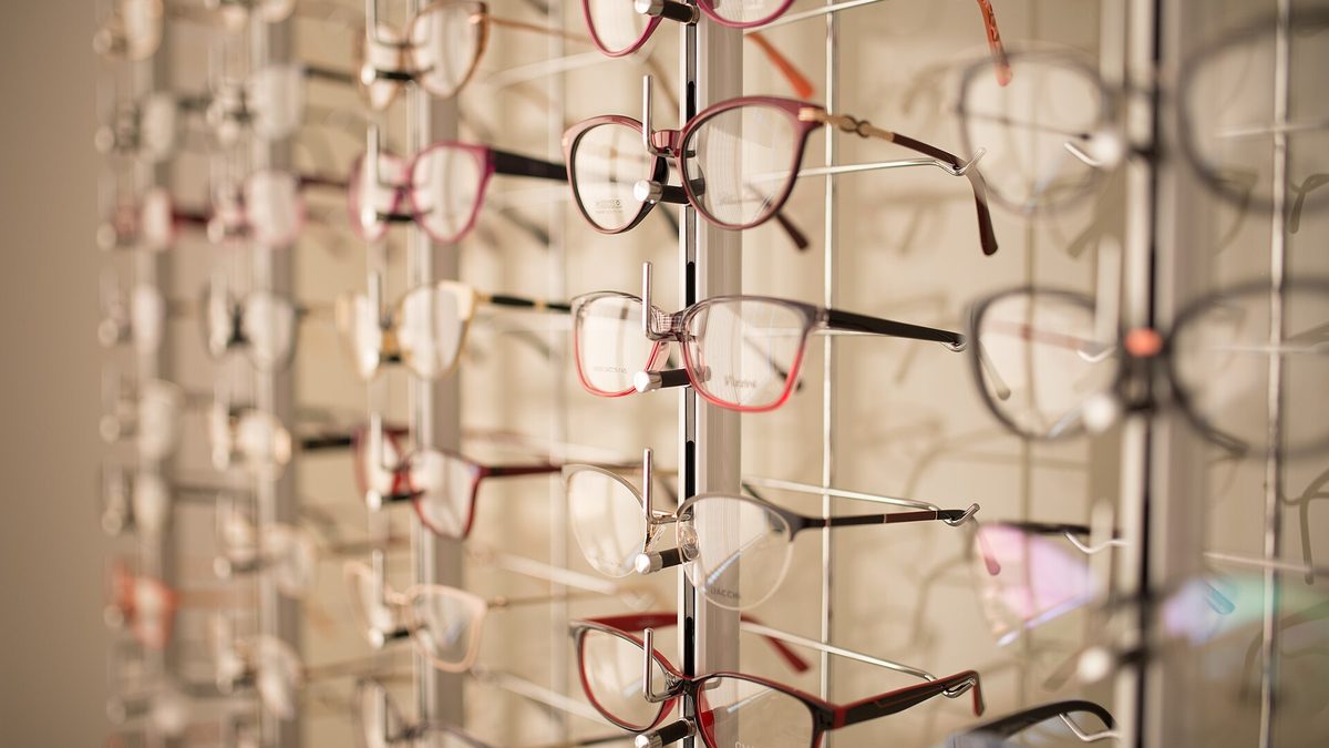 Brillengestelle in verschiedenen Formen und Farben an einer Präsentationswand beim Optiker