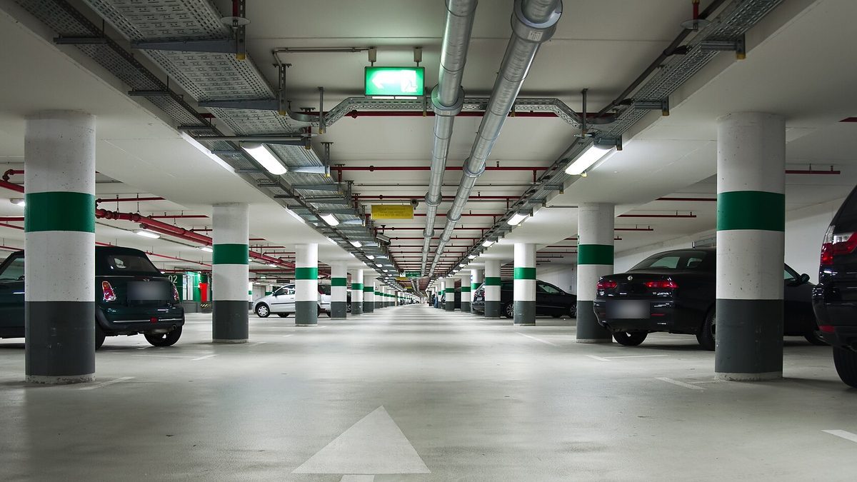 Helle Tiefgarage mit grün-weißen Säulen, Fahrgasse und geparkten Autos