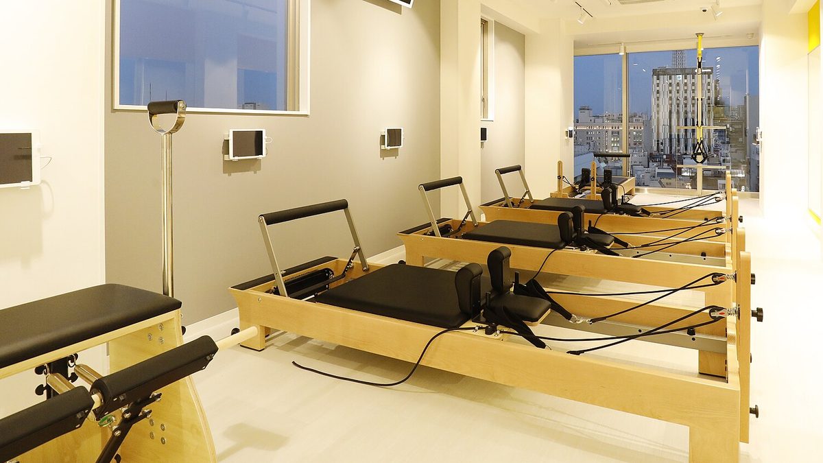Heller Pilates-Raum mit mehreren Reformer-Geräten aus Holz in einer Reihe