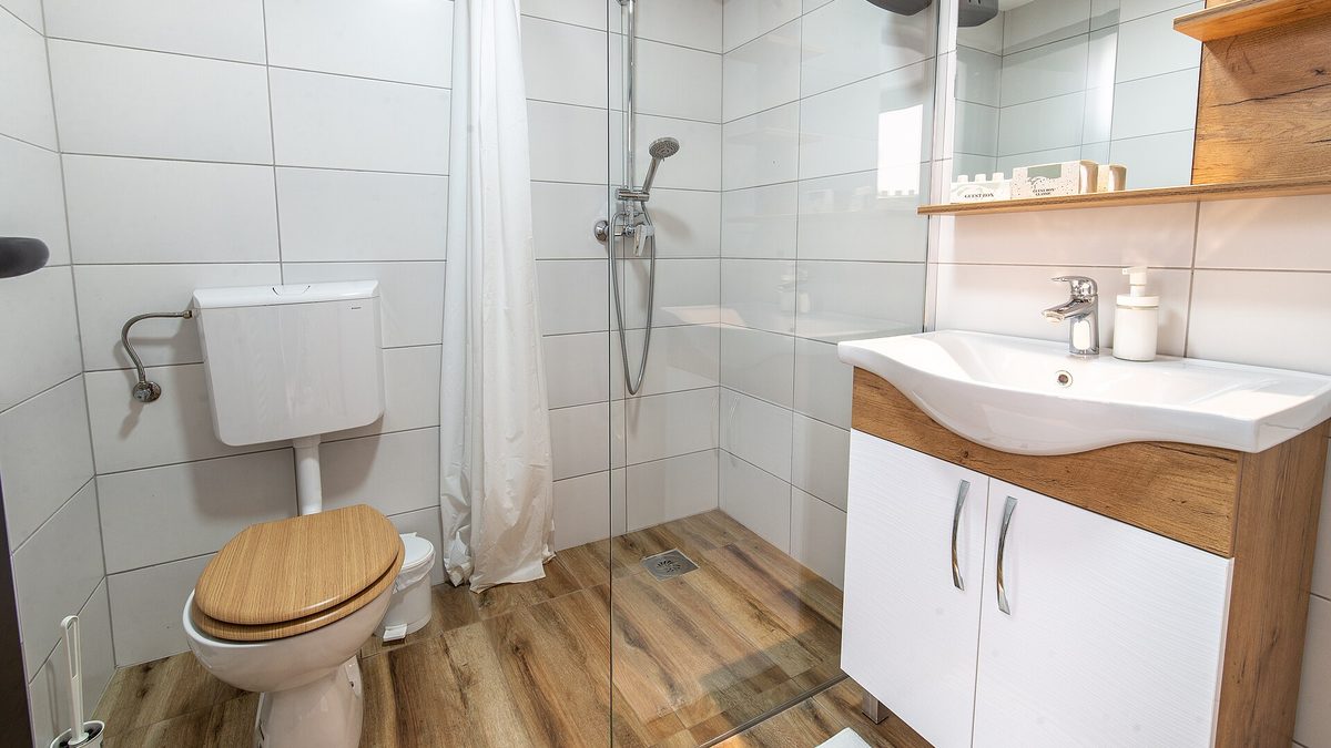 Modernes helles Badezimmer mit bodengleicher Dusche, Waschtisch und Toilette